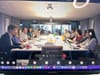 People gathered around a meeting table as seen from another computer screen online.